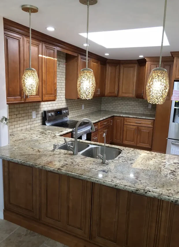Kitchen with three glass pendant lights over the island and recessed ceiling lights
